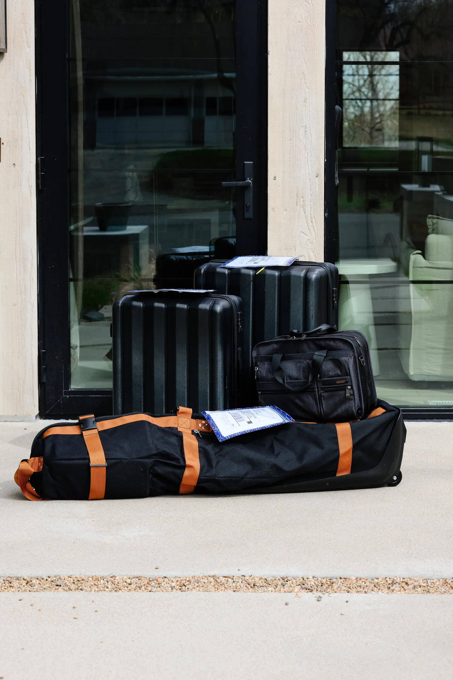 Golf travel bag and suitcase staged on the doorstep for pickup